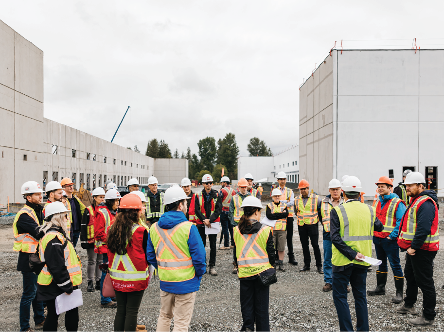 Large group of people at construction site wearing PPE.