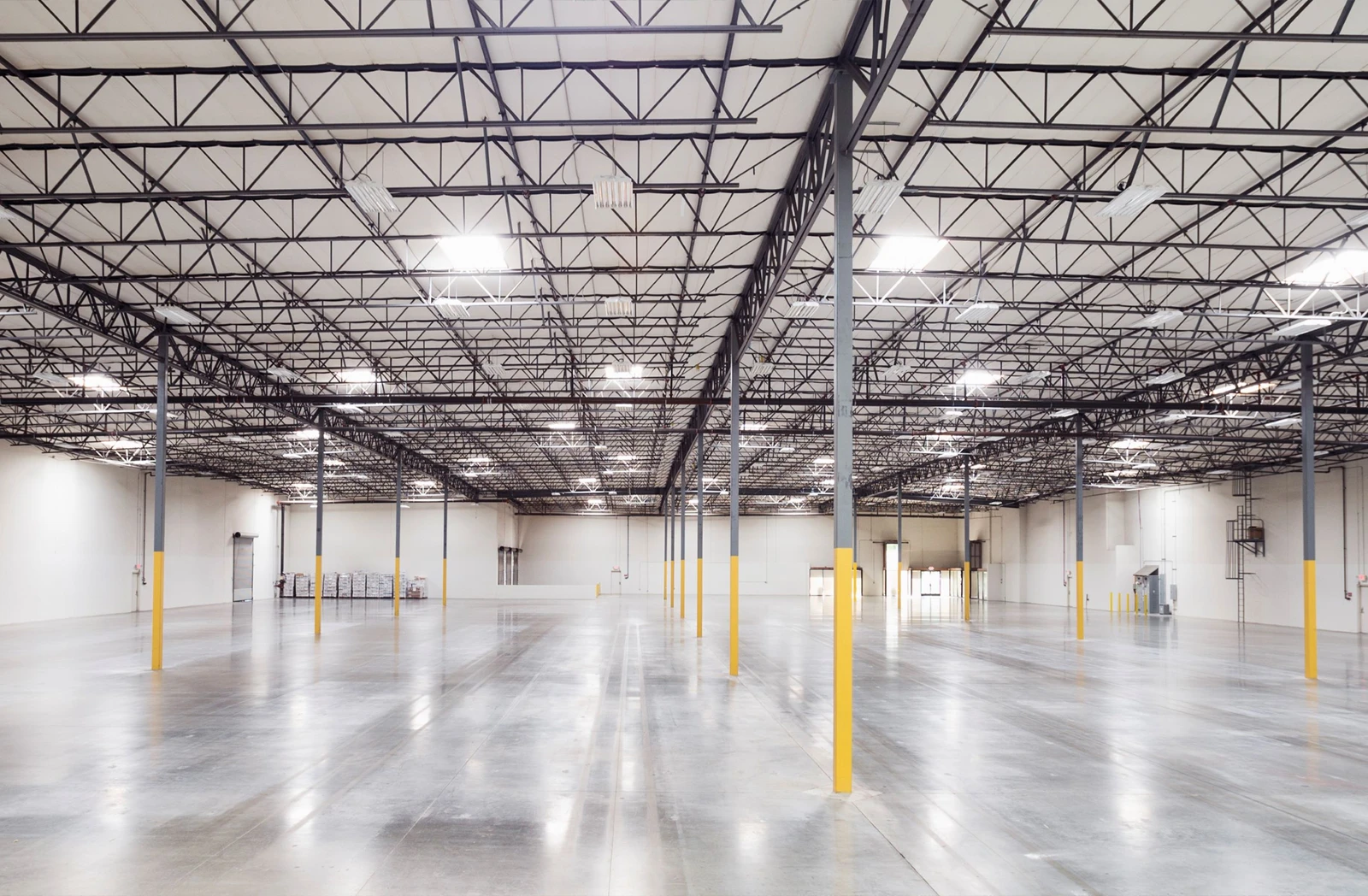 Wide view of an empty, modern urban logistics warehouse with high ceilings, LED lighting, and polished concrete floors, representing part of Valor and QuadReal’s sustainable London portfolio.