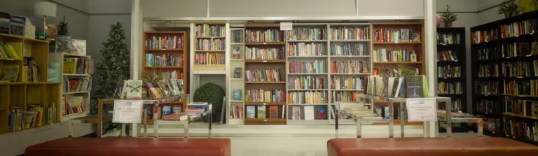 Bookshelves filled with colorful books behind two display tables and benches in a bright bookstore.