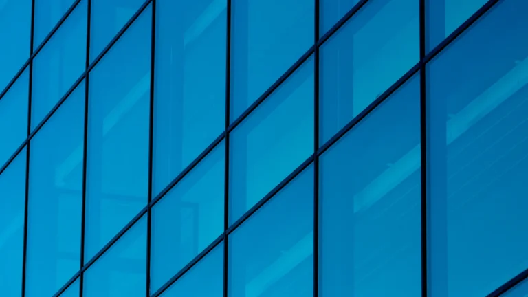Close-up of a modern commercial building façade with blue glass panels and reflective windows.