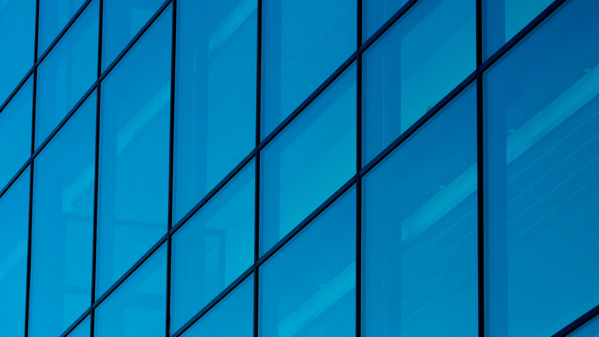 Close-up of a modern commercial building façade with blue glass panels and reflective windows.