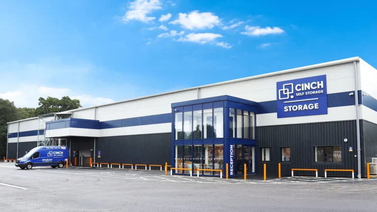 Exterior of a modern Cinch Self Storage building with a glass reception entrance and blue‑and‑white signage.