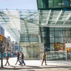 An outdoor scene with people and a modern glass building.