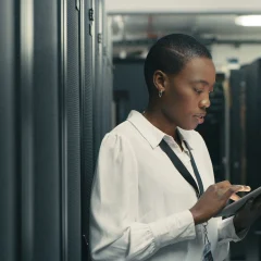 A person in a server room using a tablet.