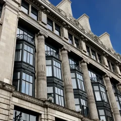 Classical-style building with bay windows and ornate stonework under a clear blue sky.