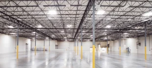 Wide view of an empty, modern urban logistics warehouse with high ceilings, LED lighting, and polished concrete floors, representing part of Valor and QuadReal’s sustainable London portfolio.